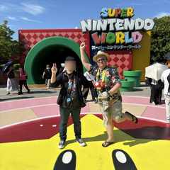 Me and my brother at the entrance to Super Nintendo World, Universal Studios Japan. He is doing a peace sign with his right hand. I am pretending to jump like Mario.