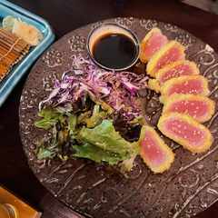 Tuna katsu, small slices of tuna with breadcrumbs on the outside, with a side of lettuce and onions.