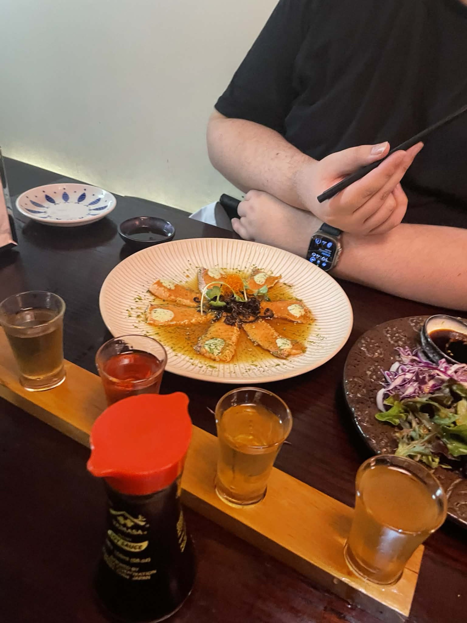 Salmon tataki. Small, thin slices of salmon sitting on a plate arranged like a flower.